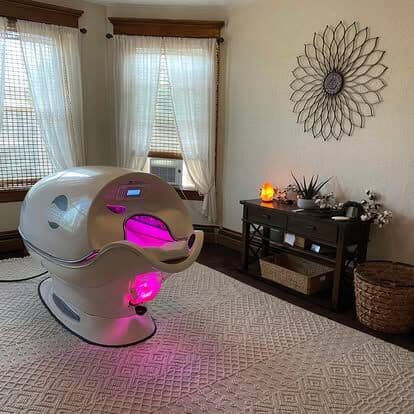 A calm treatment room at Harbor Light with the Cocoon wellness pod, an armchair and soft window light