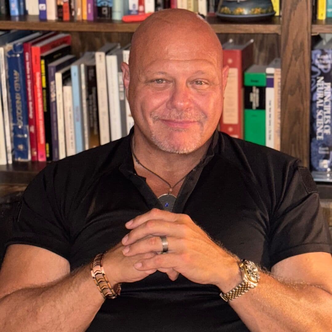 Dr. Ken Erickson, hands folded, in front of a bookshelf